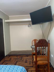 Habitación con cama y TV en la pared. en Habitación doble, en Pisco