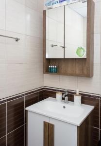 La salle de bains est pourvue d'un lavabo blanc et d'un miroir. dans l'établissement New Colorful 1BD Getaway with an Amazing Sea View, à Varna