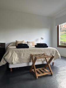 um quarto branco com uma cama e uma mesa de madeira em Las Lavandas em Ushuaia