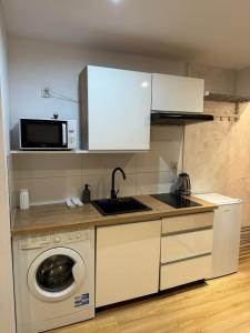 a kitchen with a washing machine and a microwave at Apartamenty Dworcowe Stacja Centrum Kielce in Kielce