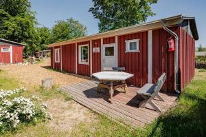 a red cabin with a picnic table and chairs on a deck at Herzmuschel in Ueckeritz