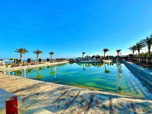 a large pool of water with palm trees and chairs at Davinci Beach Hotel in Hurghada