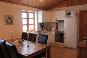 a kitchen with a wooden table and a white refrigerator at Arabær Holiday Home in Arabaer