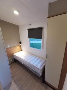 een kleine kamer met een bed en een raam bij Stacaravan op 5 Sterren Vakantiepark De Kuilart Friesland aan het Meer met Zwembad 5P 116 in Koudum