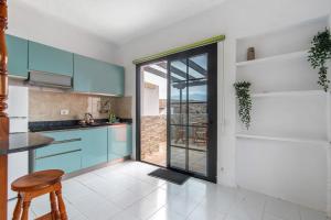 una cocina con armarios azules y una gran puerta de cristal en Faro de Sardina Frente al Mar, en Gáldar