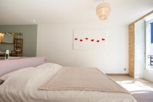 a white bedroom with a bed and a window at Le Pavean in Beaune