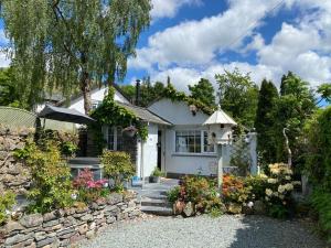 a white house with a stone wall and a bird house at Marys Cottage, Grasmere, Dog Friendly, Hot Tub in Grasmere