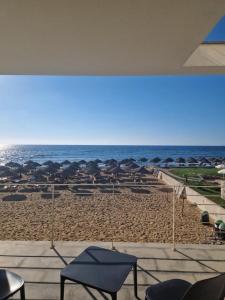 トラーパニにあるBaia dei Mulini Resort & Spaのビーチの景色を望む客室で、椅子とパラソルが備わります。