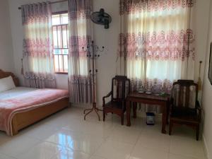 1 dormitorio con 1 cama, 2 sillas y mesa en Nhà Nghỉ Hải Nam en Dien Bien Phu