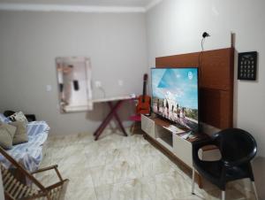 ein Wohnzimmer mit einem Flachbild-TV und einem Stuhl in der Unterkunft Pico do Jaraguá in São Paulo