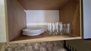 a cabinet with plates and glasses on a shelf at Achei Casa 6: Seu espaço exclusivo em Porto Velho in Porto Velho