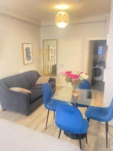 ein Wohnzimmer mit einem Sofa und einem Glastisch mit blauen Stühlen in der Unterkunft Stylish studio on Edgware Road (Marylebone) in London
