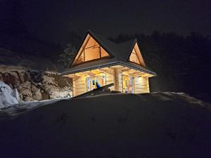 a house in the snow at night at Domek na zboczu in Ochotnica Górna