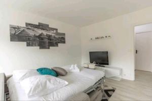 une chambre blanche avec un lit et une télévision à écran plat dans l'établissement * Cosy & Spacieux * (75 M2) RER D à 5 min à pied, à Corbeil-Essonnes