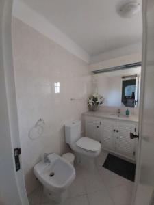 a white bathroom with a toilet and a sink at Albufeira - Casa Balaia Resort in Albufeira