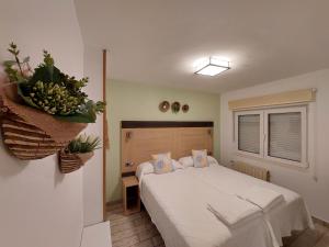 1 dormitorio con cama blanca y ventana en Pensión Cabezas, en Lugones