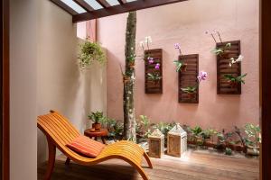 eine Terrasse mit einem Stuhl und Topfpflanzen an einer Wand in der Unterkunft Pousada Quarto Crescente in Trancoso