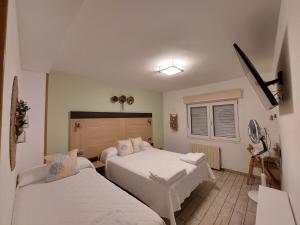 1 dormitorio con 2 camas y ventana en Pensión Cabezas, en Lugones