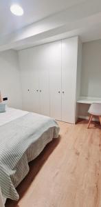 a white bedroom with a bed and a chair at Laralva Home in Pontevedra