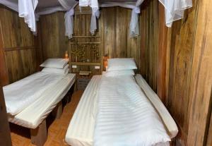two beds in a room with wooden walls at Homestay Chân Núi in Sa Pả