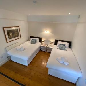 two beds in a room with white walls and wooden floors at Farmers Arms in Taunton