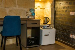 a desk with a blue chair next to a small refrigerator at Sea Holly Gozo in Nadur