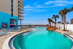 a swimming pool at a resort with palm trees and a building at Majestic Beach Resort Tower 1 #915 in Panama City Beach