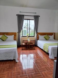 a hotel room with two beds and a window at RICE HOUSE HUE in Hue