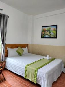 a bedroom with a white bed with a green blanket at RICE HOUSE HUE in Hue
