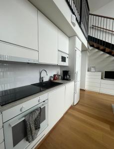a kitchen with white cabinets and a sink at Spacious loft apartment with a lake view in Tampere