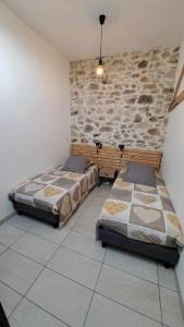 two beds in a room with a stone wall at Les Coccinelles in Adilly