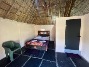 a bedroom with a bed and a chair in a room at Hippie Land Nature Stay in Hampi
