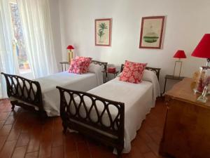een slaapkamer met 2 bedden en 2 tafels en lampen bij Villa Bianca in Porto Ercole