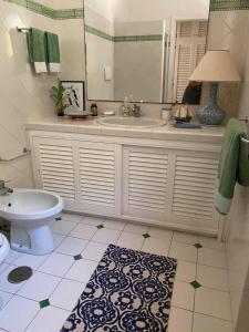 een badkamer met een wastafel, een toilet en een spiegel bij Villa Bianca in Porto Ercole