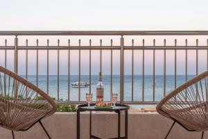 a balcony with two chairs and a table and the ocean at Kohili Suite Stegna Beach in Archangelos
