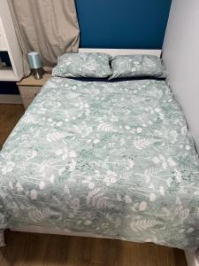a bed with a green and white comforter at Nice and Pleasant in Thornton Heath