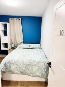 a bedroom with a bed with a blue wall at Nice and Pleasant in Thornton Heath