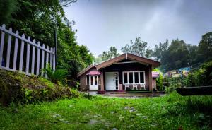 a small house with a fence in a yard at Woodside Bungalow1 in Ooty