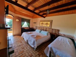 a bedroom with two beds and a wooden ceiling at Hotel Pousada Boa Montanha in Monte Verde