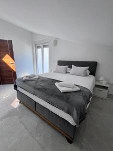 a white bedroom with a large bed with two towels on it at SeaScape Deluxe Residence in Pješčana Uvala 