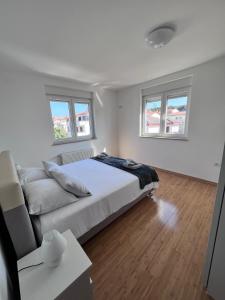 a white bedroom with a bed and a couch at SeaScape Deluxe Residence in Pješčana Uvala 