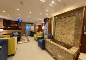 Zad al Bait Hotel في مكة المكرمة: غرفة معيشة كبيرة مع أرائك وجدار حجري