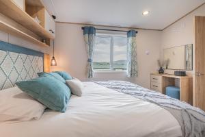 - une chambre avec un grand lit blanc et une fenêtre dans l'établissement Beverley Holiday Caravan, à Bassenthwaite