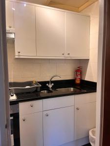 uma cozinha com armários brancos e um lavatório em Ullet Suites em Liverpool
