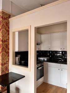 uma cozinha com armários brancos e uma mesa preta em Ullet Suites em Liverpool