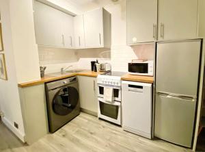 a kitchen with white cabinets and a stainless steel refrigerator at Cozy 1 bed in the heart of South Kensington in London