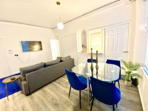 a living room with a glass table and blue chairs at Cozy 1 bed in the heart of South Kensington in London