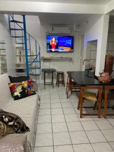 uma sala de estar com uma mesa e uma televisão na parede em Casa geminada 1 em Florianópolis
