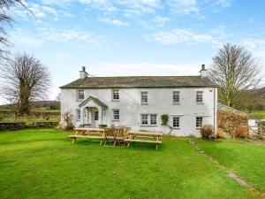 a large white house with picnic tables in the yard at 5 Bed in Threlkeld SZ270 in Threlkeld