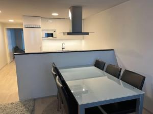 een witte tafel en stoelen in een kamer met een keuken bij Moderni perhehuoneisto parhaalla sijainnilla in Espoo
